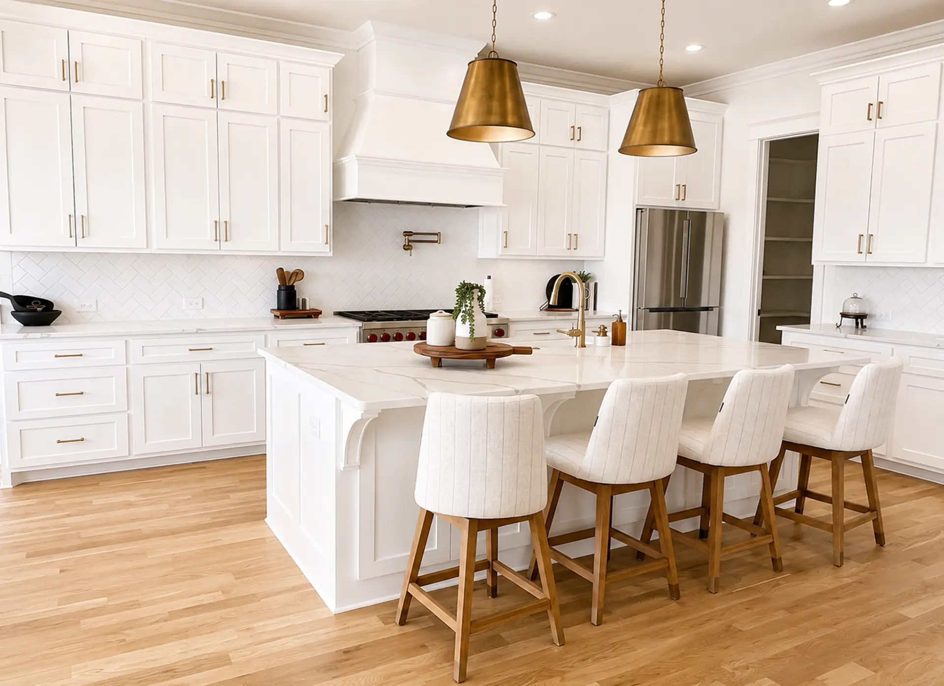 White shaker kitchen with brass pendants, marble island, and oak flooring